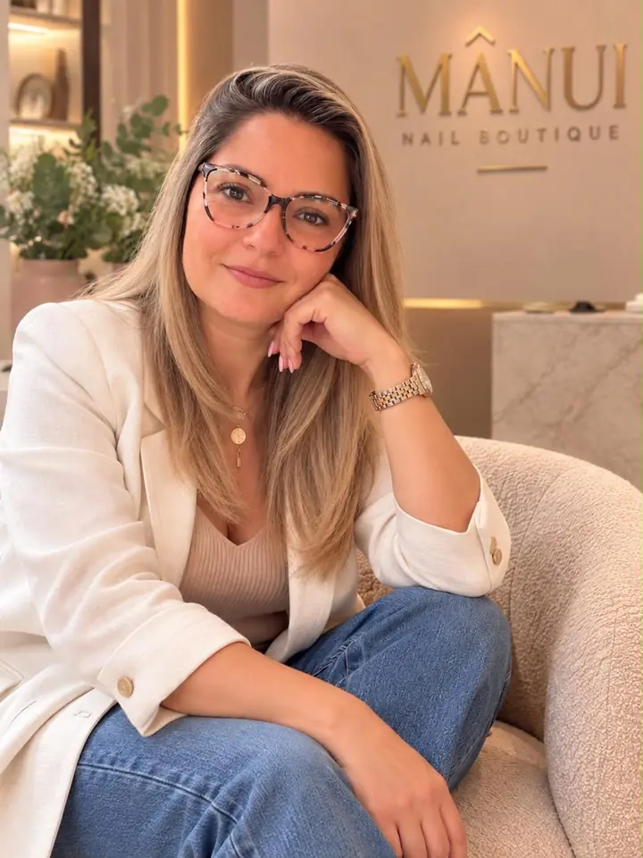 Daniela Johnson, fundadora de MÂNUI, sentada en un sillón frente al logo de la marca